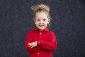 skön liten blond flicka i en röd klänning leende. fem år gammal barn. foto