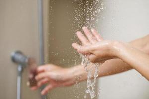 en kvinna användningar hand till mäta de vatten temperatur från en vatten värmare innan tar en dusch foto
