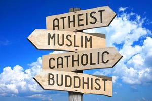 ateist, muslim, katolik, buddist - religion begrepp - trä- vägvisare med fyra pilar foto