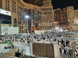 mecka, saudi Arabien, Mars 2023 - en stor siffra av umrah pilgrimer i främre av de klocka torn i masjid al haram. foto