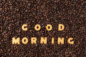 orden god morgon från kexbokstäver på en mörk kaffebönabakgrund foto