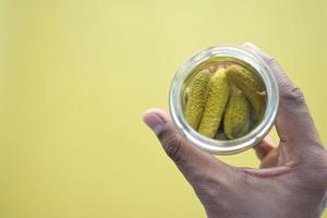 flaska inlagda gurkor, pickles på bordet foto