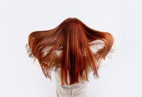 tillbaka se av en ung skön kvinna rörande henne röd hår på vit bakgrund, kopia Plats foto