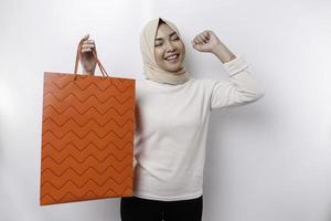 asiatisk muslim kvinna Lycklig skön ung stående upphetsad innehav en handla väska, studio skott isolerat på vit bakgrund foto