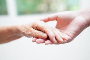 asiatisk ung pojke innehav gammal mormor kvinna hand tillsammans med kärlek och vård. foto