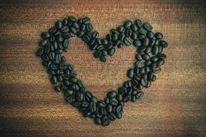 kaffe böna i hjärta form på trä- tabell foto
