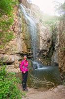 leende kvinna Framställ i främre av stor vattenfall i de stenar foto