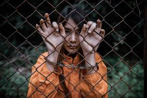 fånge i orange dräktkoncept, porträtt av asiatisk kvinna i fängelseuniformer på vit bakgrund, foto