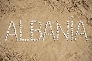albania - ord tillverkad med stenar på sand foto