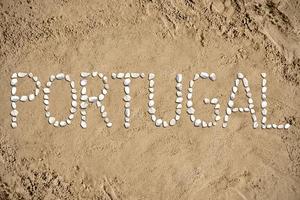 portugal - ord tillverkad med stenar på sand foto