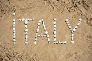 Italien - ord tillverkad med stenar på sand foto