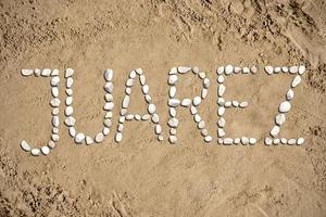 juarez - ord tillverkad med stenar på sand foto