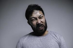 asiatisk stilig man arg på vit bakgrund, porträtt av ung påfrestning manlig begrepp foto