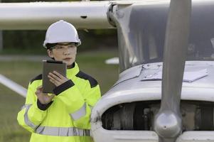 tekniker som fixar motorn på flygplanet, kvinnlig flygteknik som kontrollerar flygplansmotorer, asiatisk mekaniker underhåll inspekterar flygmotorn foto