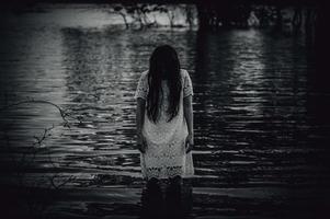porträtt av asiatisk kvinna göra upp spöke ansikte på de träsk, skräck i vatten scen, skrämmande på flod, halloween affisch, thailand människor foto