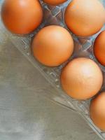 närbild Lycklig påsk se färsk brun kyckling rå ägg flera i ägg låda plast på en tabell cement mönster loft Färg för matlagning. friska äter foto