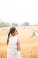 ung asiatisk kvinnor i vit klänningar i de korn ris fält foto