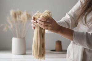 närbild skott av en kvinnas hand innehav en knippa av rå spaghetti över en tabell under lunch förberedelse, ai genererad foto