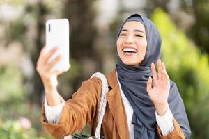 muslim kvinna vinka till de mobil utomhus foto