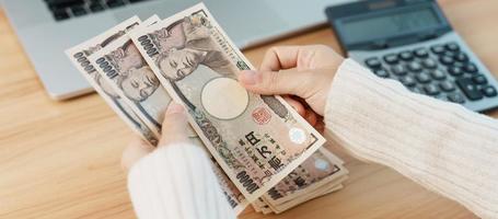 kvinna hand räkning japansk yen sedel med kalkylator. tusen yen pengar. japan kontanter, beskatta, lågkonjunktur ekonomi, inflation, investering, finansiera, lön och betalning begrepp foto