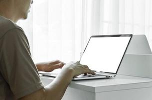 mannens händer använder sig av bärbar dator med tom skärm på vit tabell på Hem eller kontor. foto