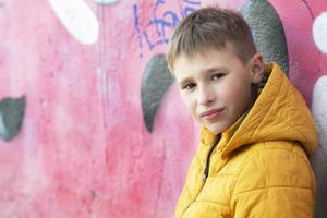 pojke tonåring nära de vägg med graffiti. foto