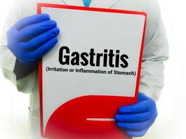 läkare innehav en notera vaddera med medicinsk termin gastrit, inflammation av mage Inklusive matsmältnings tarmkanalen. foto