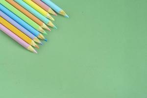 pastell färgad pennor, topp se på grön bakgrund, illustration begrepp, utbildning och tillbaka till skola foto