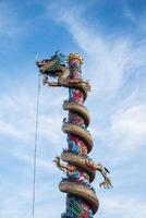 färgrik kinesisk drake staty vrida de pelare eller Pol på wat sangkat rattana khiri i thailand på blå himmel bakgrund foto
