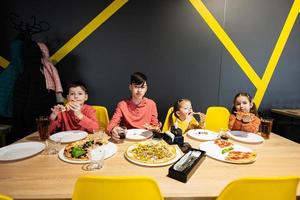 fyra barn äter italiensk pizza i pizzeria. barn äta på Kafé. foto