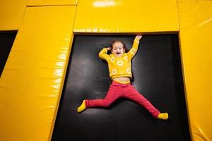 bebis flicka unge liggande på trampolin på lekplats parkera. barn i rörelse under aktiva underhållning. foto