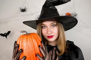 halloween banner med kvinna klänningar som en häxa innehav pumkin på bakgrund med spindelnät foto