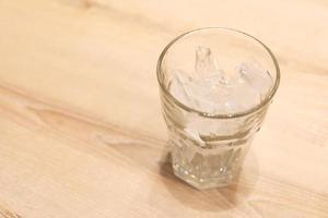 is i ett tömma glas på en trä- tabell. is i glas. foto
