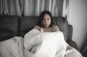 asiatisk sjuk kvinna sitta i soffan stanna hemma,kvinnan mådde dåligt, ville ligga och vila,hög feber foto