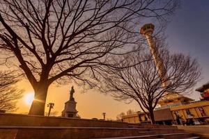 se av busan torn med staty av yi sol-synd i främre på blå himmel bakgrund med träd. foto