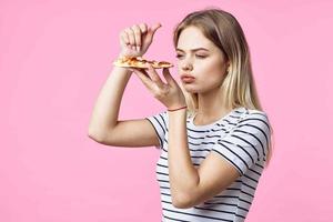 glad kvinna med snabb mat i henne händer snacks utsökt rosa bakgrund foto