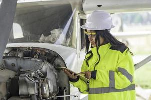 tekniker som fixar motorn på flygplanet, kvinnlig flygteknik som kontrollerar flygplansmotorer, asiatisk mekaniker underhåll inspekterar flygmotorn foto