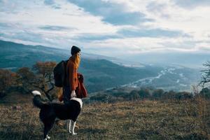 kvinna med ryggsäck på natur Nästa till hund promenad berg landskap foto