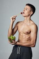 atletisk kille med en taggad torso friska mat sallad tallrik måltid träna foto