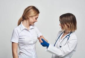 kvinna läkare i en medicinsk klänning och blå handskar undersöker en patient i en beskurna se foto