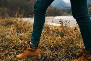 kvinna ben i stövlar och jeans på natur i höst i de bergen foto