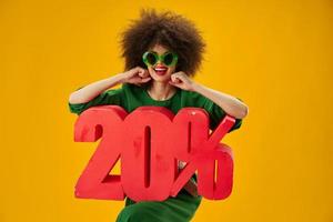 Söt kvinna grön klänning afro frisyr mörk glasögon tjugo procent i händer studio modell oförändrad foto