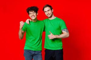 två man grön t-tröjor omfamning känslor vänskap röd bakgrund foto