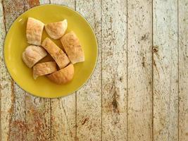 skivat bröd på en gul platta på en träbordbakgrund foto