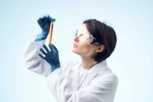 kvinna laboratorium assistent i vit täcka kemisk lösning testa rör vetenskap foto
