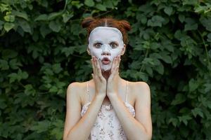 porträtt av en flicka anti rynkor mask dermatologi grön buskar bakgrund foto