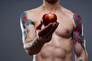 naken kroppsbyggare med pumpade muskler och tatuering äpple i hand hälsa foto