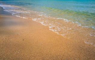 ljus blå hav vågor på en rena sandig strand. foto