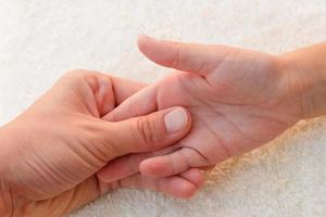 massör håller på med massage fingrar liten bebis. foto