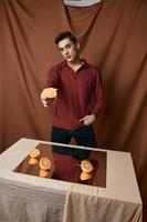 orange apelsiner på de spegel på de tabell och en man i en skjorta på en tyg bakgrund foto